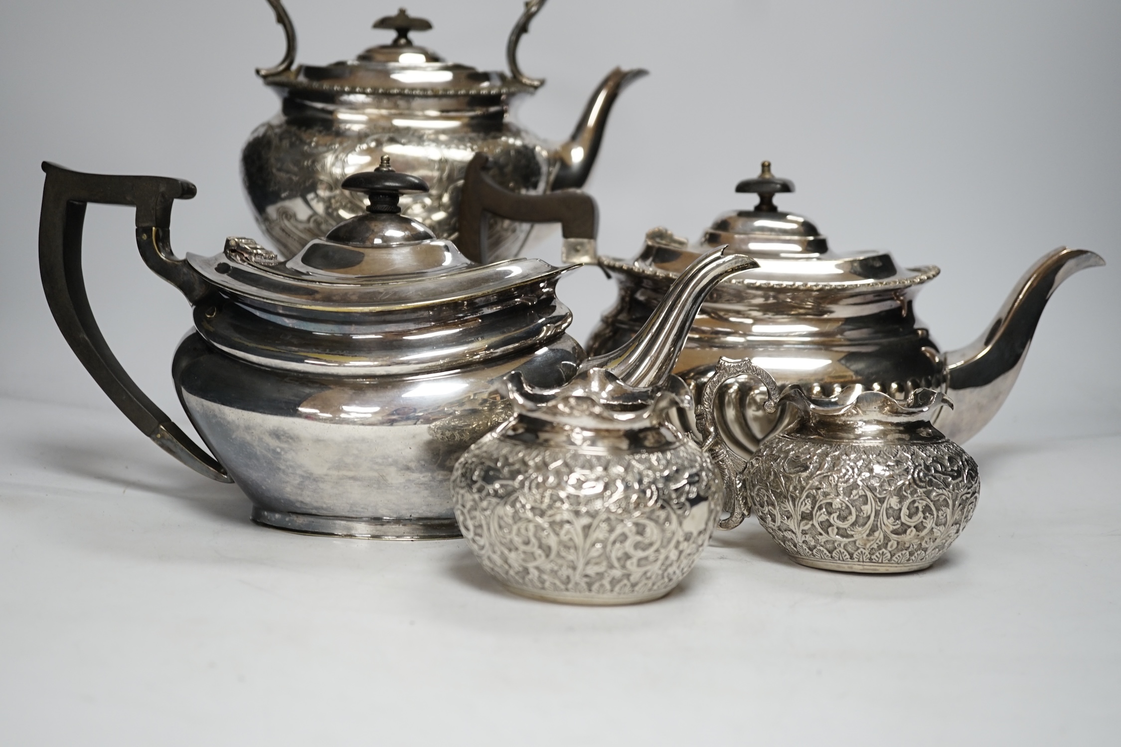 A plated kettle on stand, two plated teapots, a sugar bowl and a cream jug